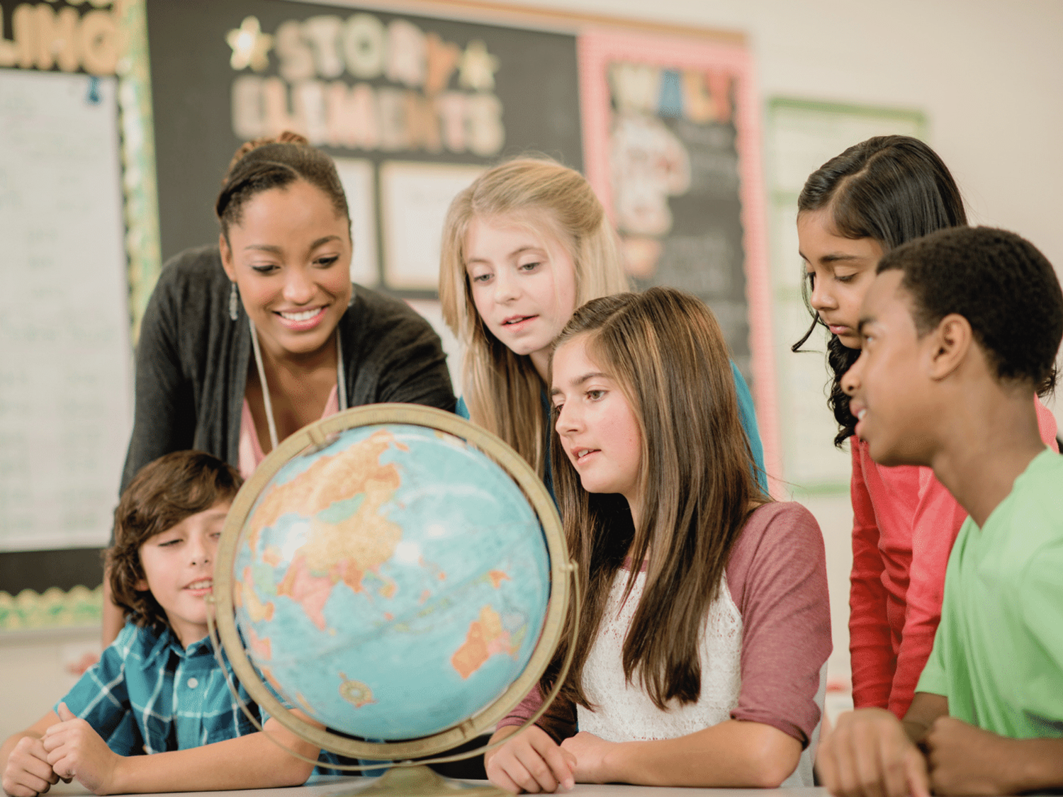 Learners and a teacher looking at a globe