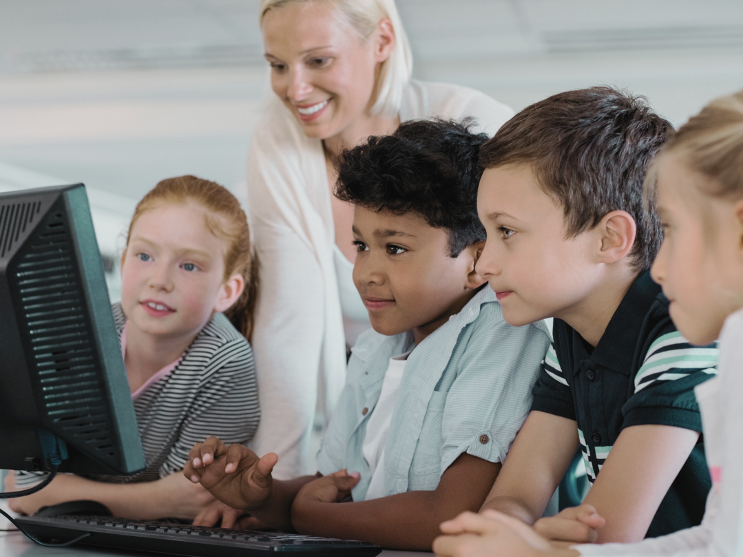 Students working with a teacher on a computer